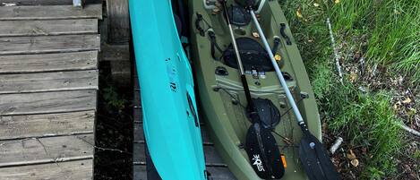A kayak and paddle leaning against a wooden dock.