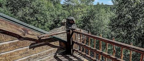 A wooden staircase leading up to a platform with a railing, surrounded by dense trees.