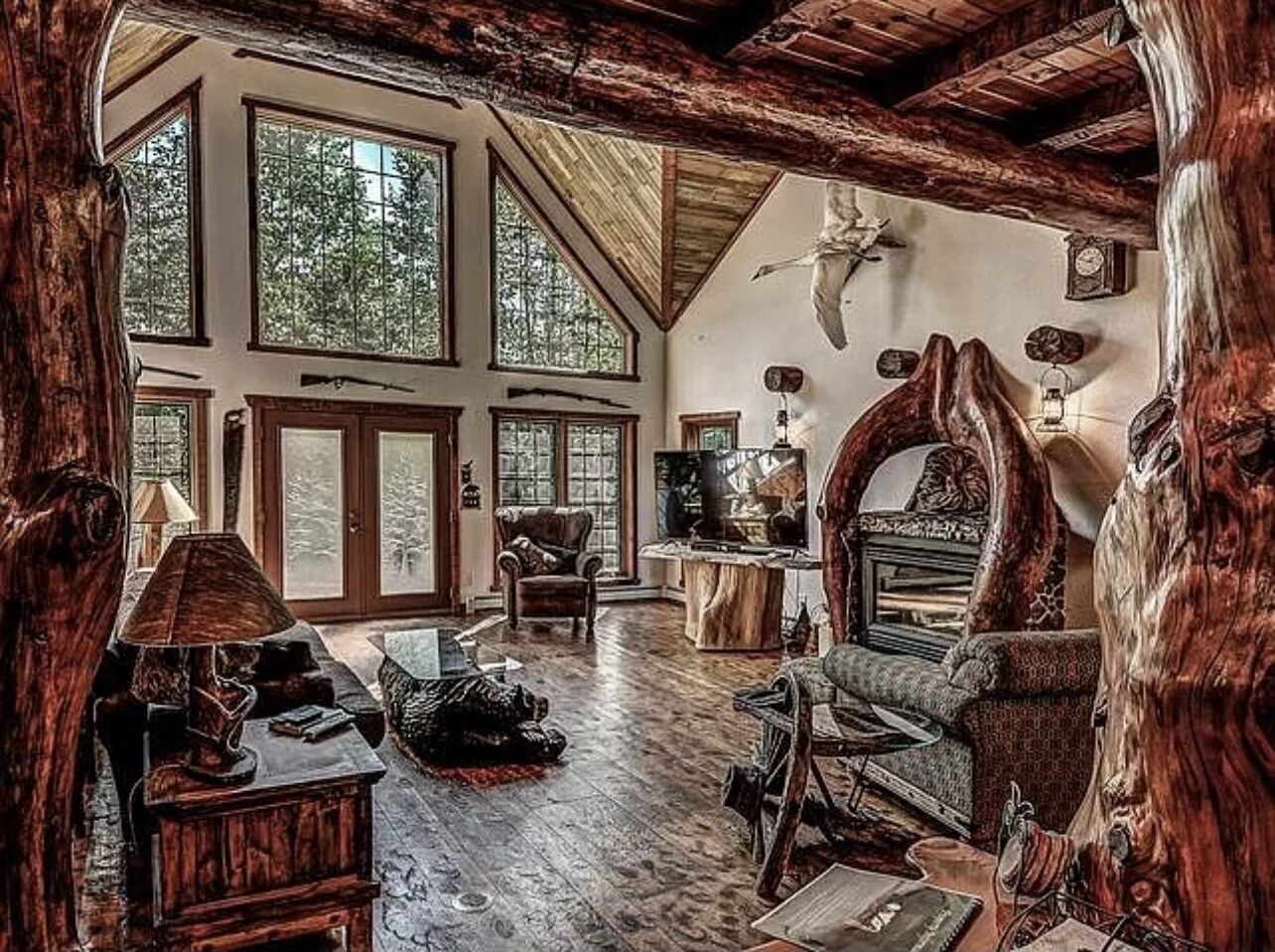 Een rustiek interieur met hoge plafonds, houten balken en grote ramen.