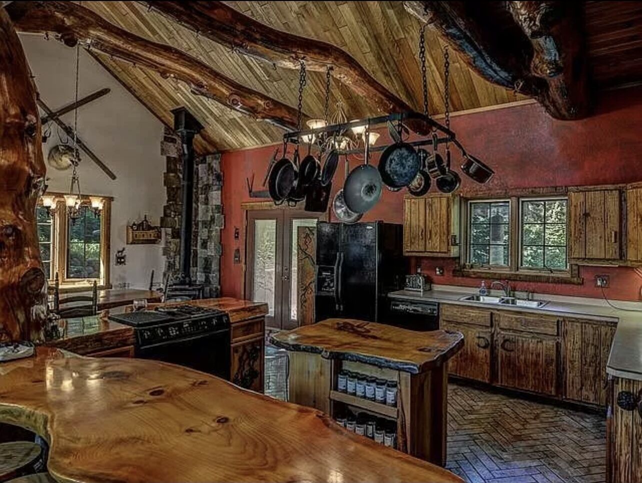 Eine rustikale Küche mit Holdekor, einer Holz Arbeitsplatte und hängenden Töpfen.