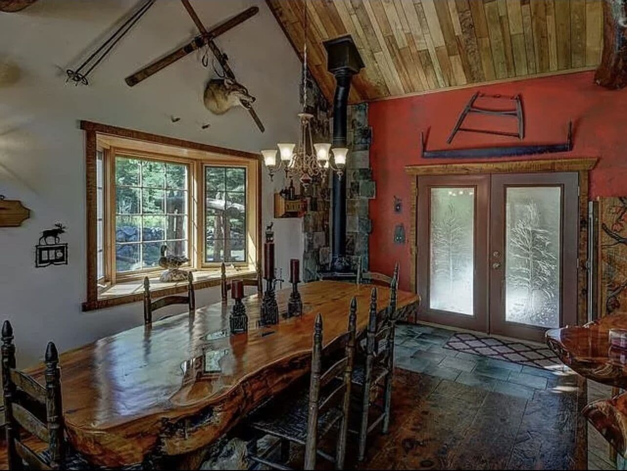 Un comedor rústico con una gran mesa de madera, un candelabro y una chimenea de piedra.