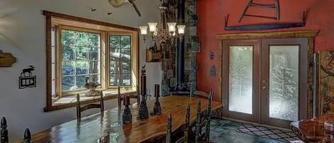 Un comedor rústico con una gran mesa de madera, un candelabro y una chimenea de piedra.