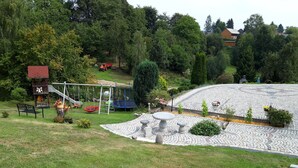 A park with a playground, a stone bench, and a circular stone pathway.