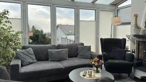 Ein modernes Wohnzimmer mit einem grauen Sofa, einem schwarzen Sessel und einem Couchtisch mit einem Blumenstrauß.