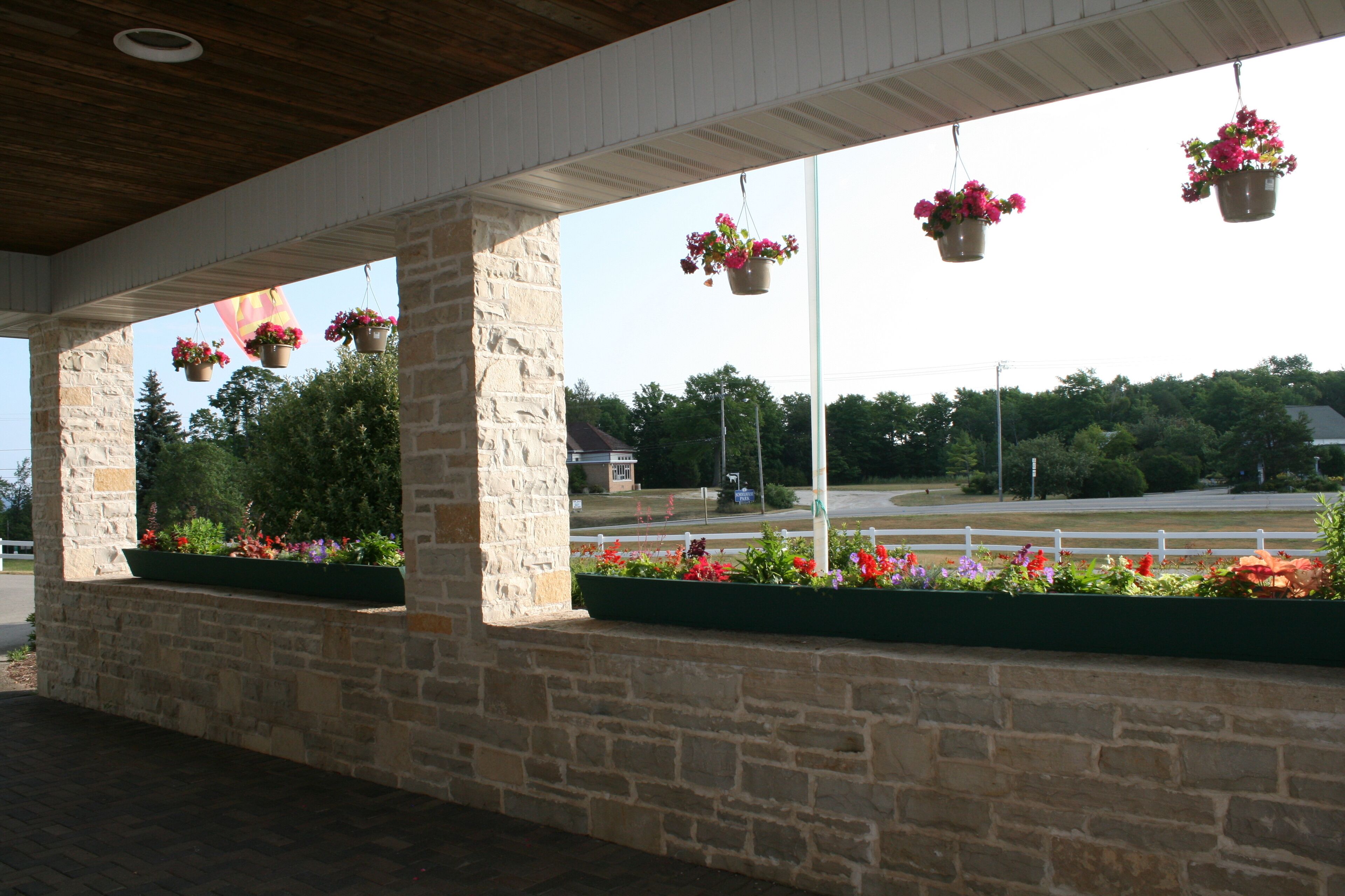 A covered outdoor area with stone walls and hanging flower baskets.