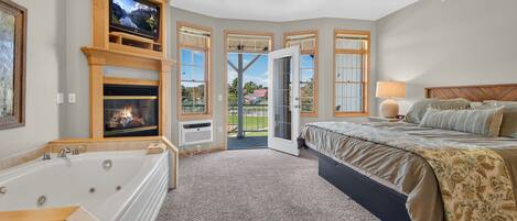 A bedroom with a fireplace, a large window, a ceiling fan, and a bed.