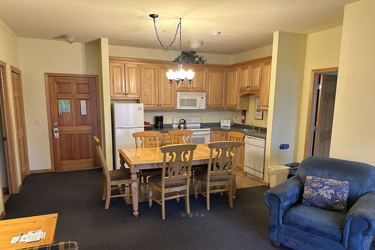 Una cocina pequeña con armarios de madera, una mesa y sillas.