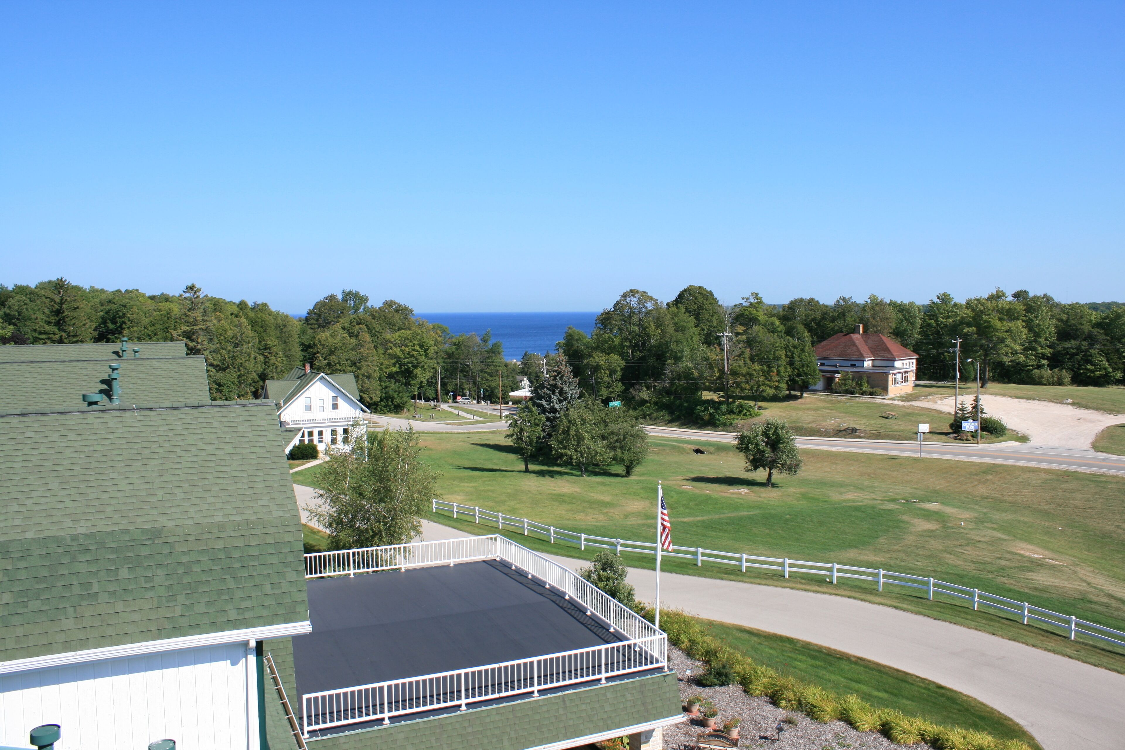 A large building with a green roof, a white fence, and a view of the ocean.