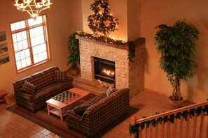 Ein gemütliches Wohnzimmer mit Kamin, zwei karierte Sofas, einem Couchtisch und einem Weihnachtsbaum.