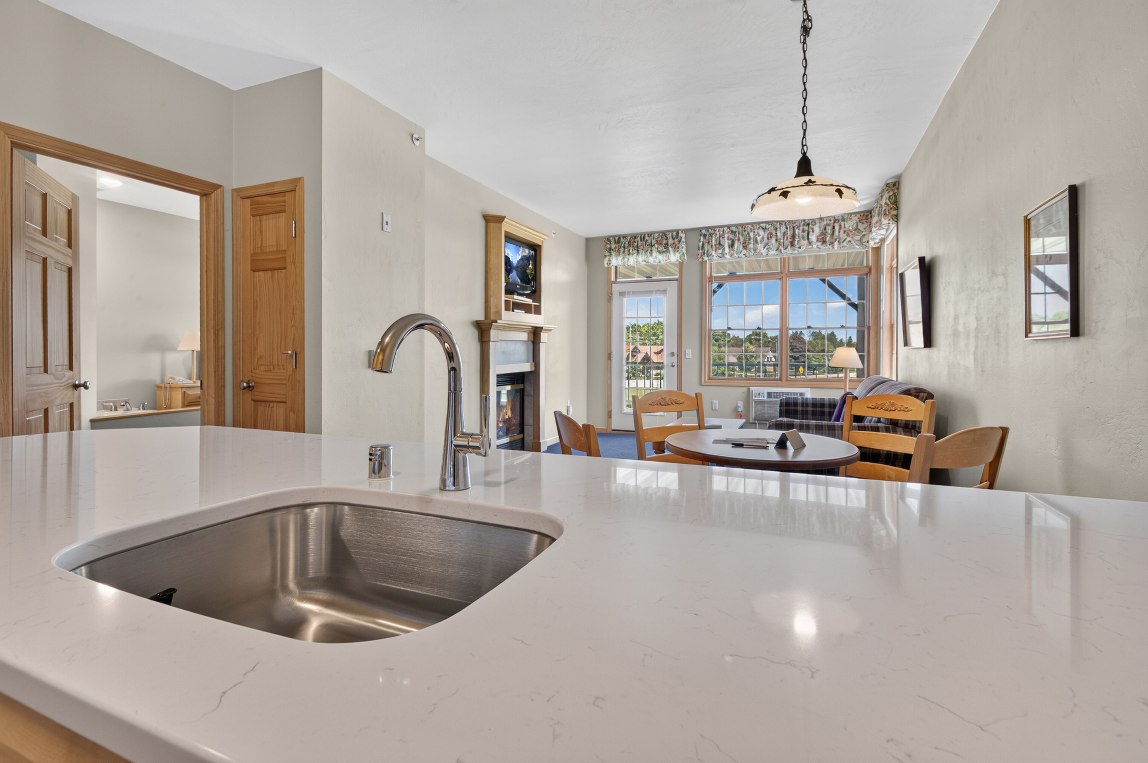 A kitchen with a large island, a built-in sink, and a dining area with chairs and a table.