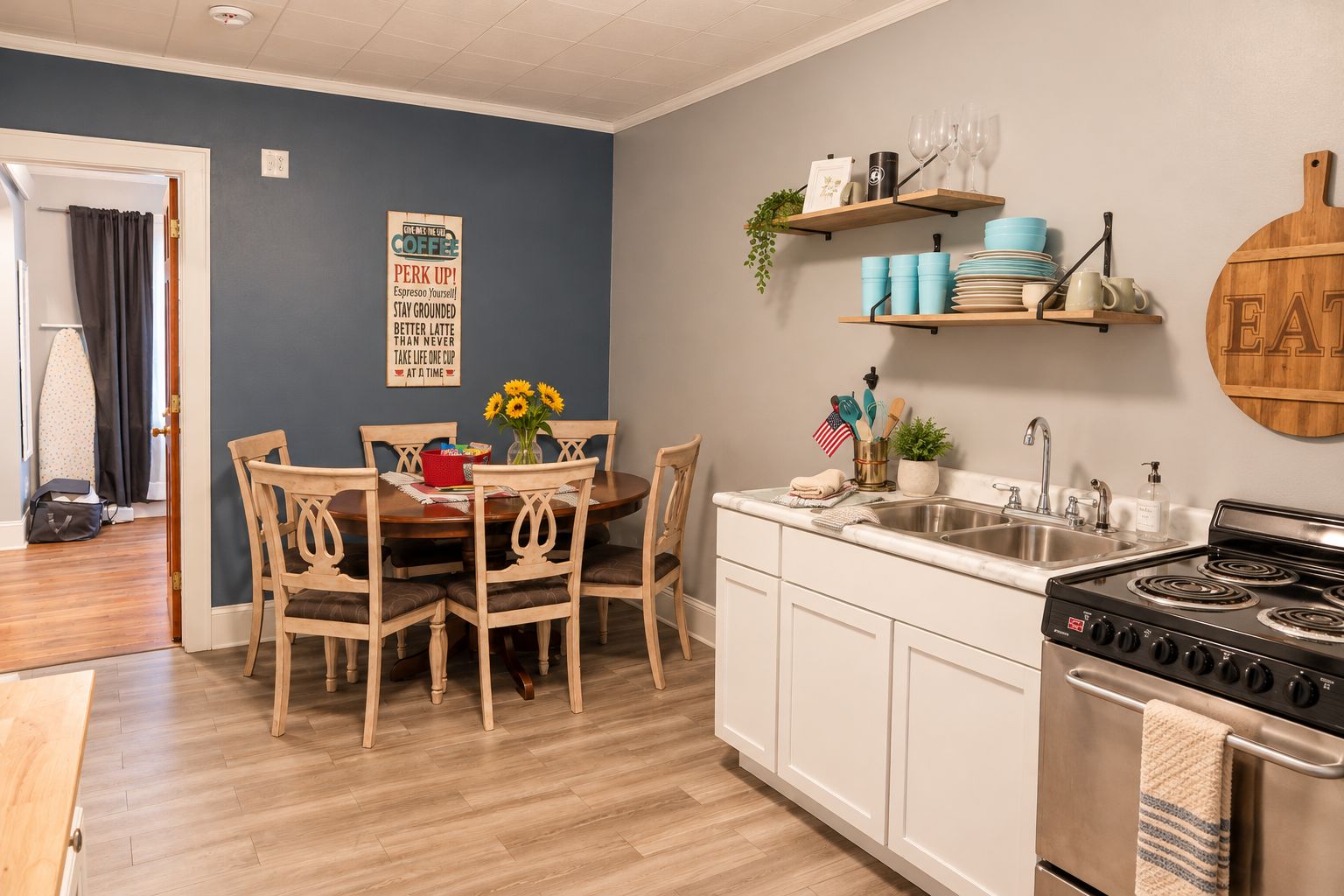 A kitchen with a dining table, chairs, a stove, and a sink.