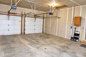 A garage with two white garage doors, a metal workbench, a broom, and a cabinet.