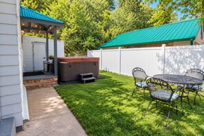Un jardin avec un jacuzzi, un patio couvert et un coin repas comprenant des chaises et une table.