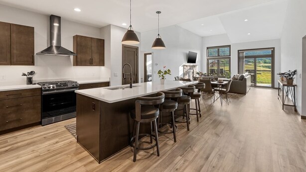 A modern kitchen with a central island, bar stools, and a dining area with a view.