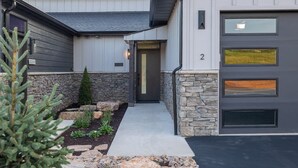 A modern two-story house with a stone facade, a front door, and a garage with three large windows.