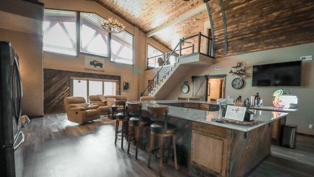 Une cuisine spacieuse dotée d’un grand îlot central, de tabourets de bar et d’un escalier menant à un niveau supérieur.