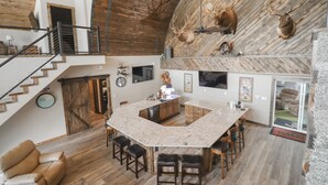 Une cuisine spacieuse avec un grand îlot central, un plafond en bois et des têtes de cerf accrochées au mur.