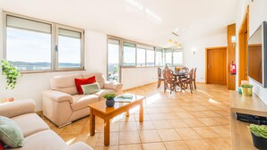 A spacious living room with a sofa, coffee table, and dining area. - Villa Alte Springs (Loulé)