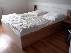 A single bed with a wooden frame and white bedding. - Stylish apartment in Stormbruch with garden (Diemelsee-Stormbruch)