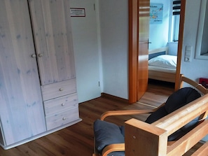 Una stanza con un armadio in legno, un letto con materasso blu e una panca di legno con cuscini.