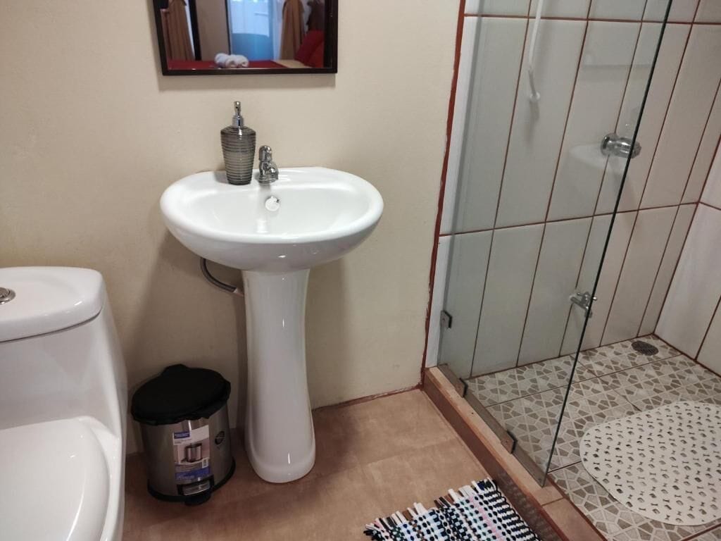 A bathroom with a white sink, toilet, and a trash can.