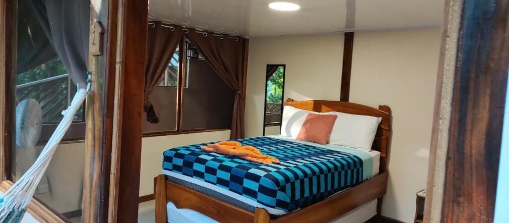 A bedroom with a bed, curtains, a window, and a fan.