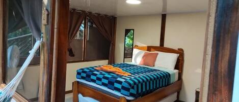 A bedroom with a bed, curtains, a window, and a fan.