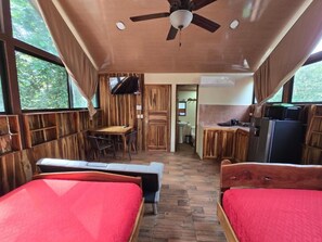 A compact room with two beds, a ceiling fan, a small table, and a kitchenette. - Cool Waters Jungle Villas (Bahía Ballena)
