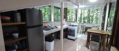 A kitchen with a refrigerator, stove, sink, and dining table.