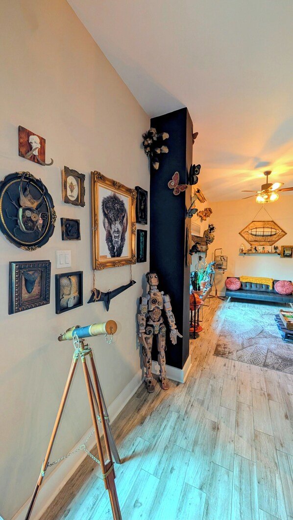 A room with a wooden floor, a telescope, and various framed artworks on the walls.
