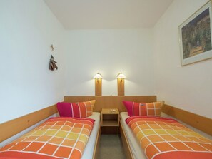 Una habitación con dos camas individuales, cada una con una colcha estampada, una mesita de noche y dos lámparas de pared.