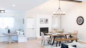 Ein modernes Wohnzimmer mit Essbereich, Kamin und einer Kristallleuchter.