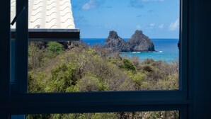 A view of a rocky coastline with a building in the foreground. - Pousada Mar em Mim (Fernando de Noronha)