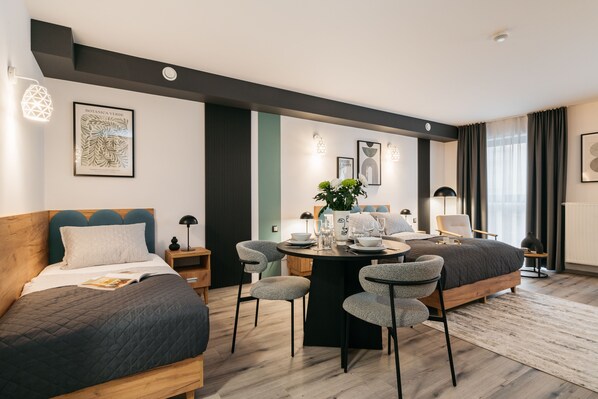 A modern hotel room with a bed, a dining table, and a seating area.