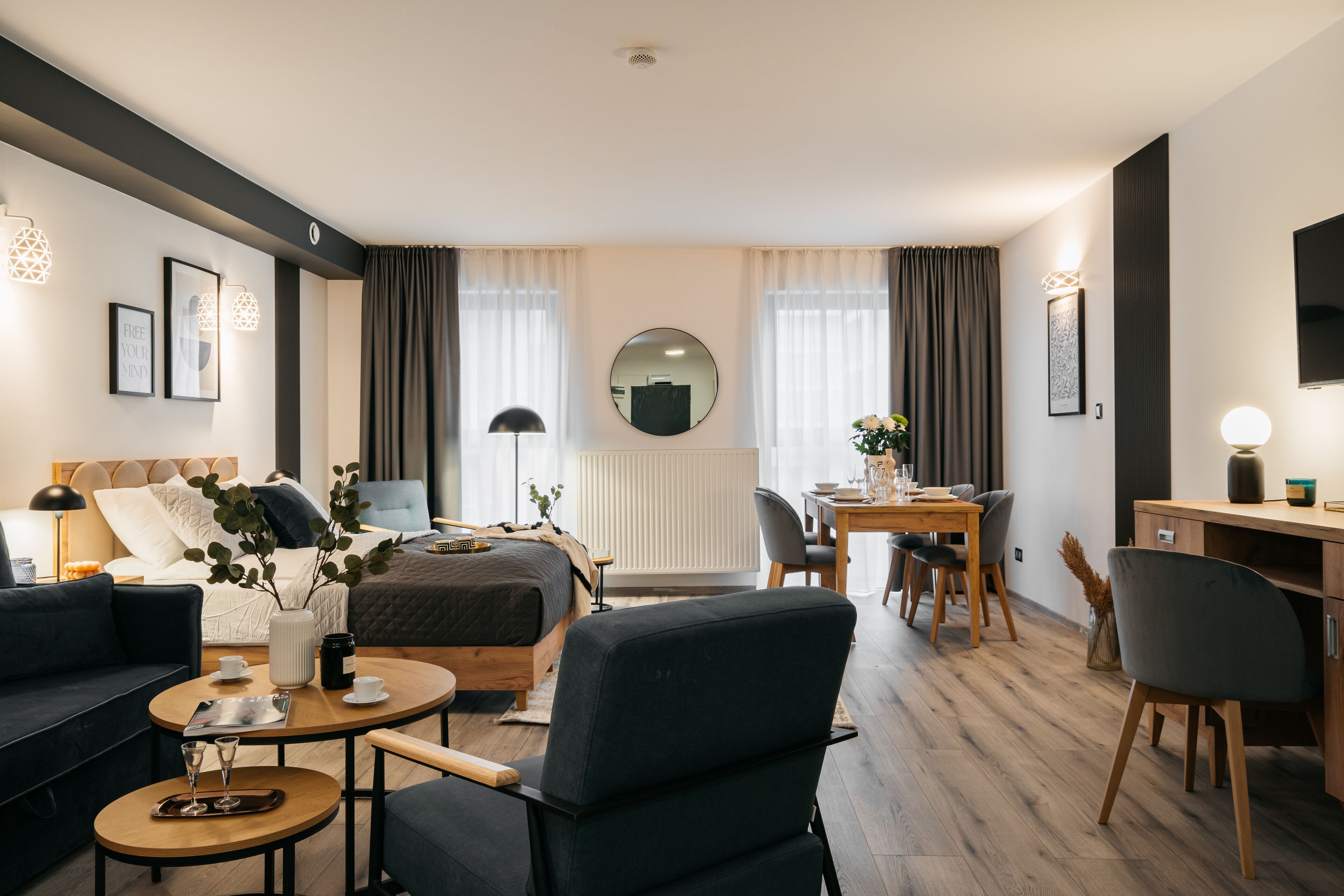 Et moderne hotelværelse med seng, sofa, spisebord og fjernsyn.