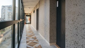 Un pasillo con piso estampado, ventanas grandes y una puerta con un letrero.