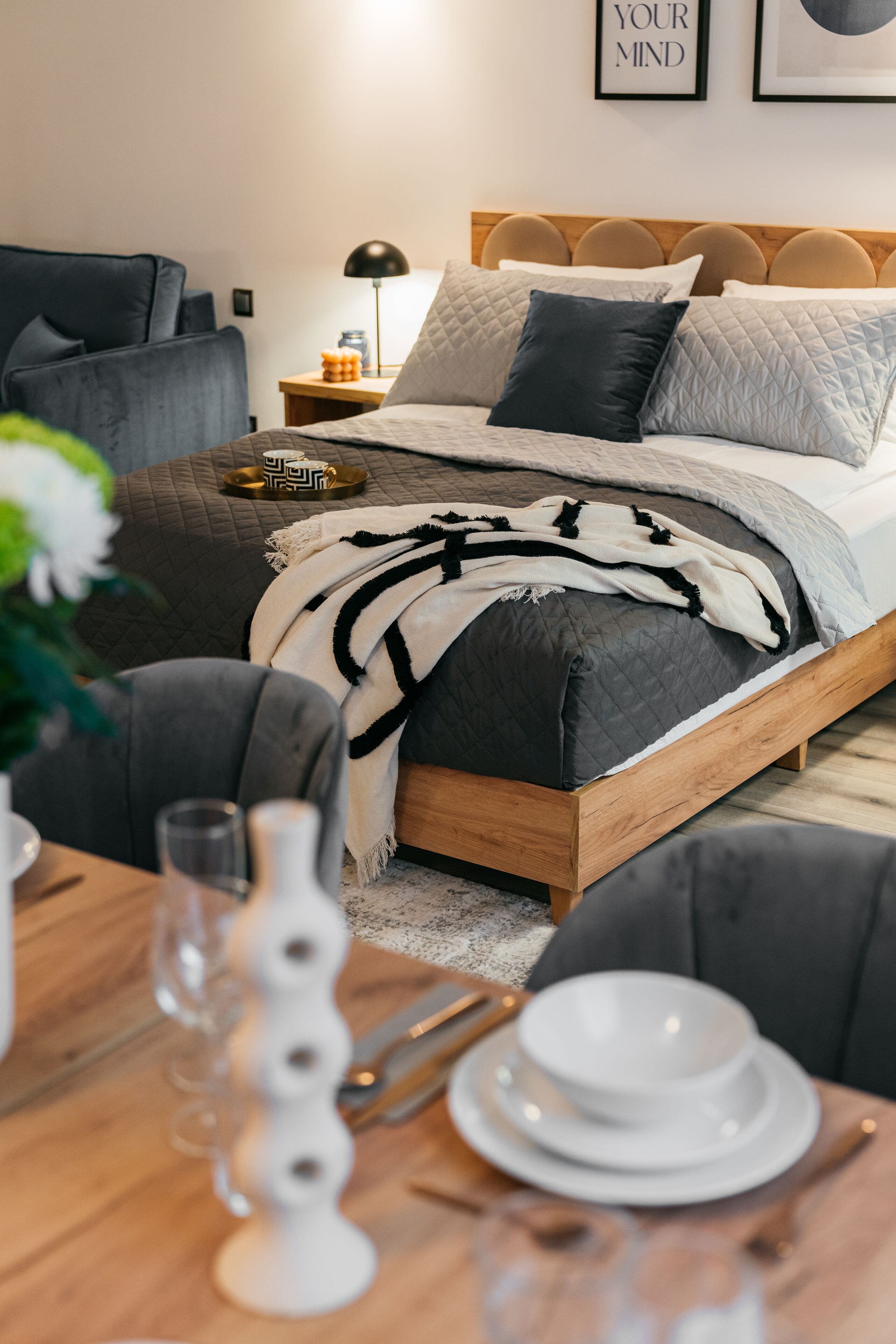 A neatly arranged bedroom with a wooden bed, a bedside table with a lamp, and a framed quote on the wall.