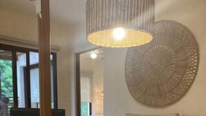 Un salon moderne avec un banc en bois à lattes, une œuvre d’art murale ronde et un luminaire suspendu.