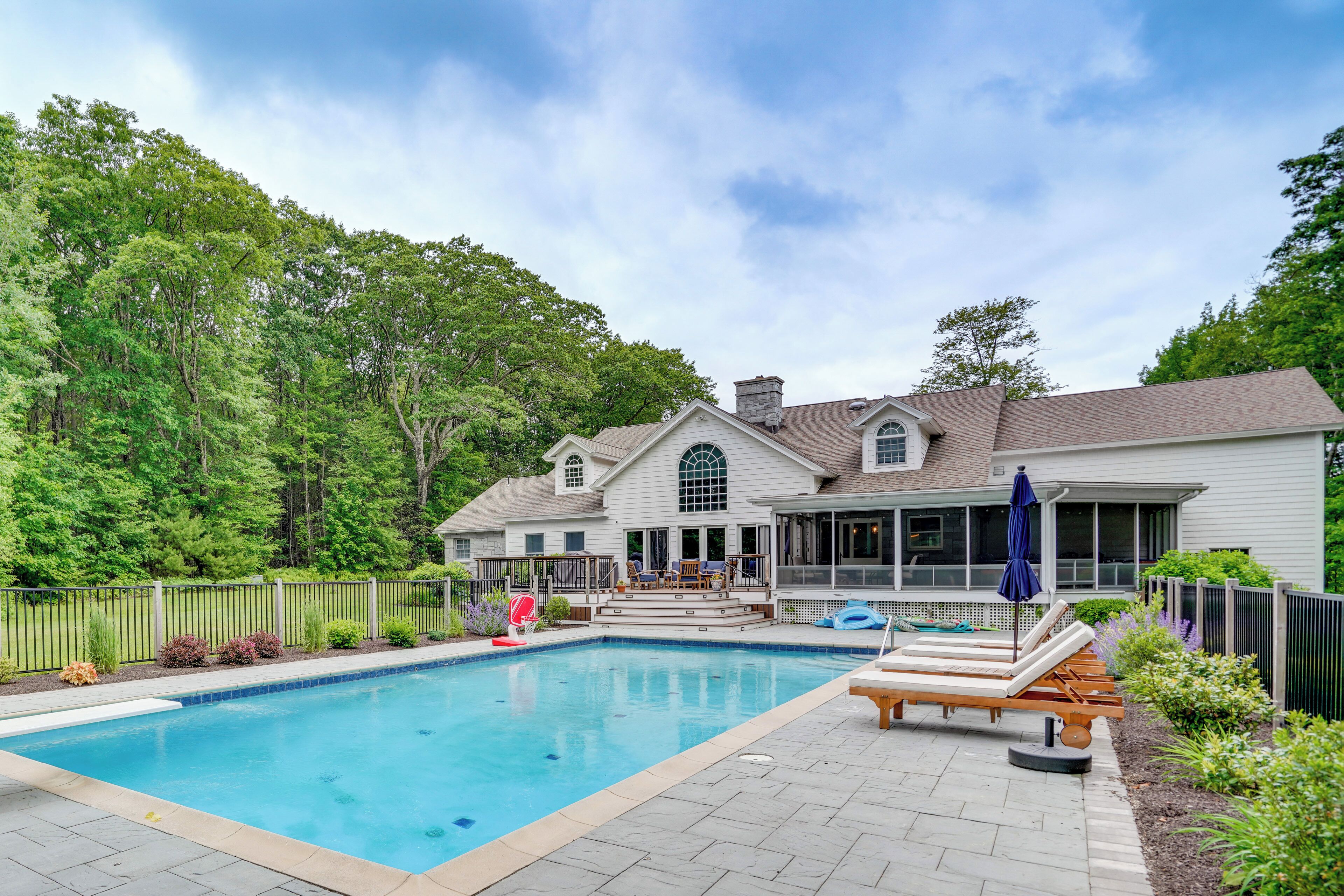 A swimming pool with lounge chairs and a covered patio area.