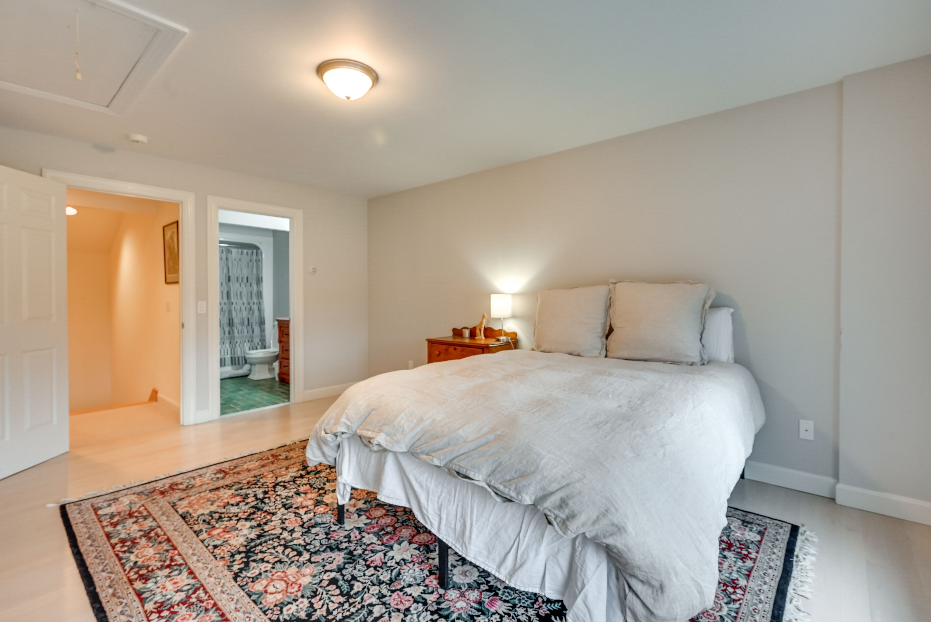Une chambre avec un grand lit, une table de chevet, une lampe et un tapis à motifs floraux.
