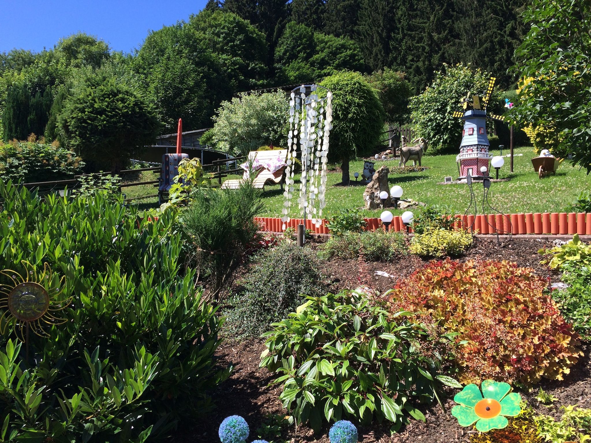 A garden with various plants, a small pond, and a decorative structure.