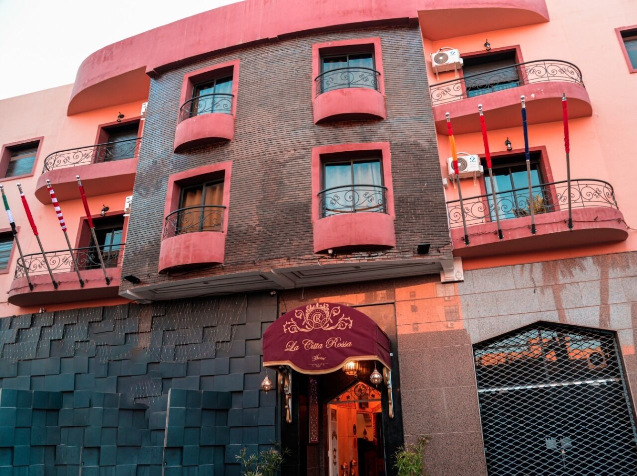 A multi-story building with a curved facade, balconies with wrought iron railings, and a ground-level entrance with a sign reading "La Città Rosa."