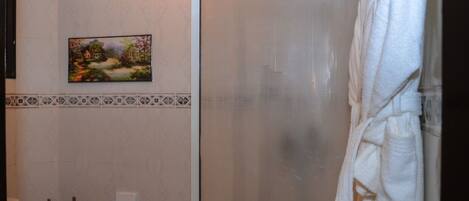 A bathroom with a toilet, a shower, and a towel rack.