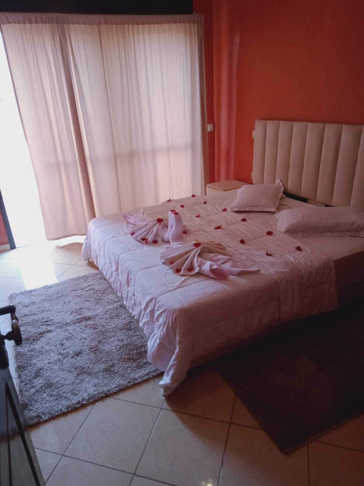 Habitación de hotel con cama, mesita de noche, una silla y ventana con cortinas.