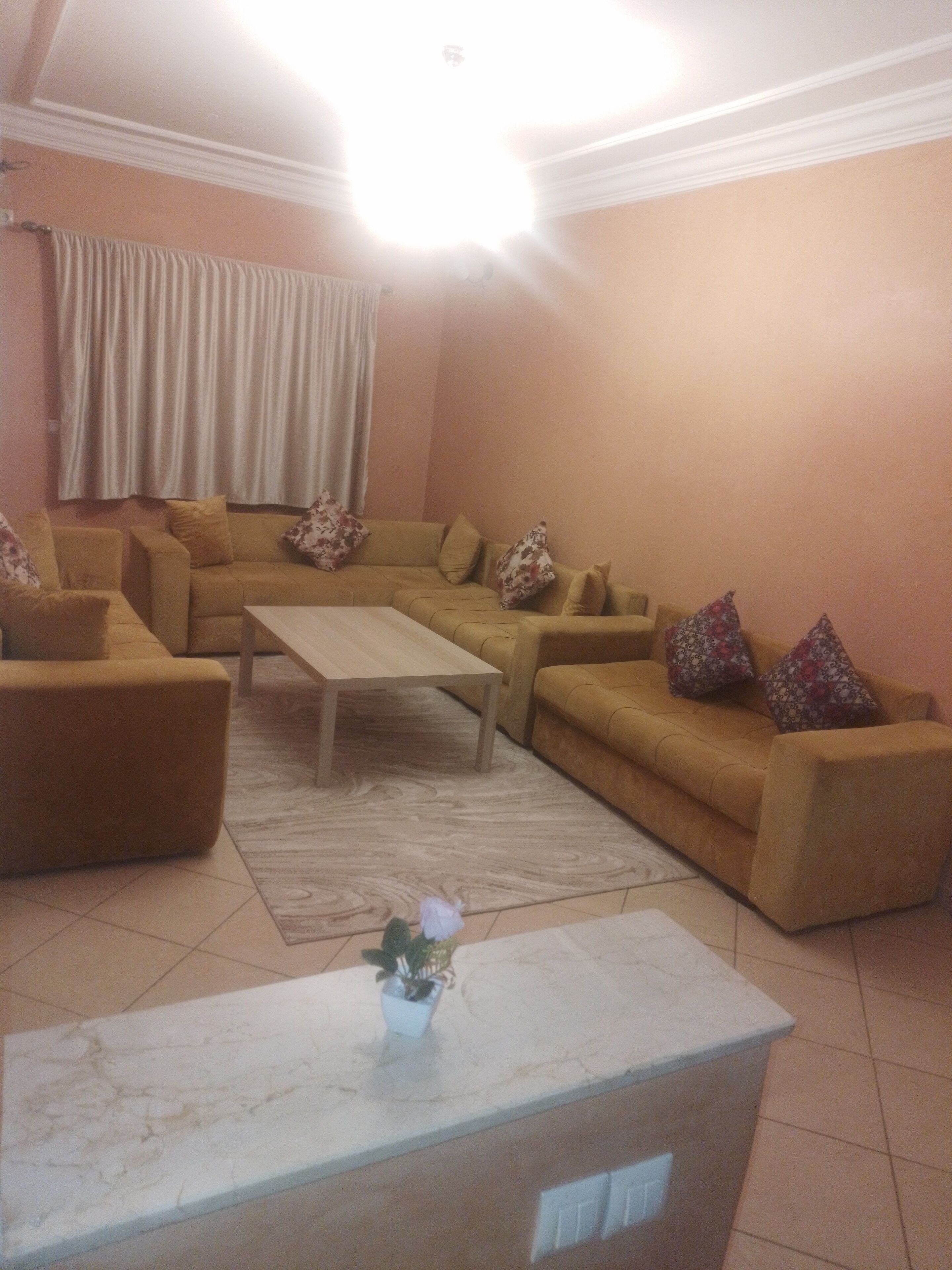 Una sala de estar con un sofá beige, una mesita de centro y una planta en maceta.