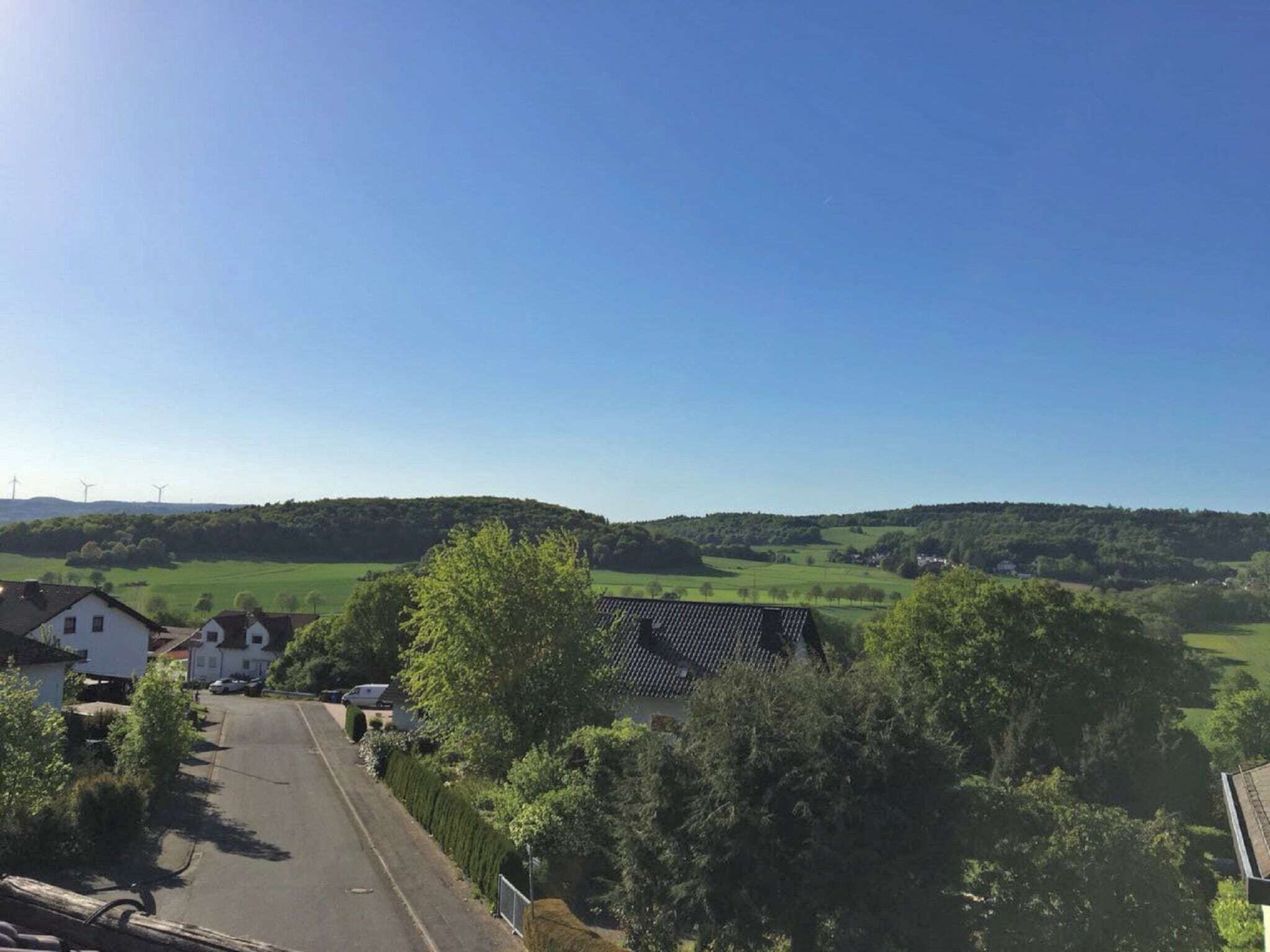 A rural landscape with houses, a road, and rolling hills.