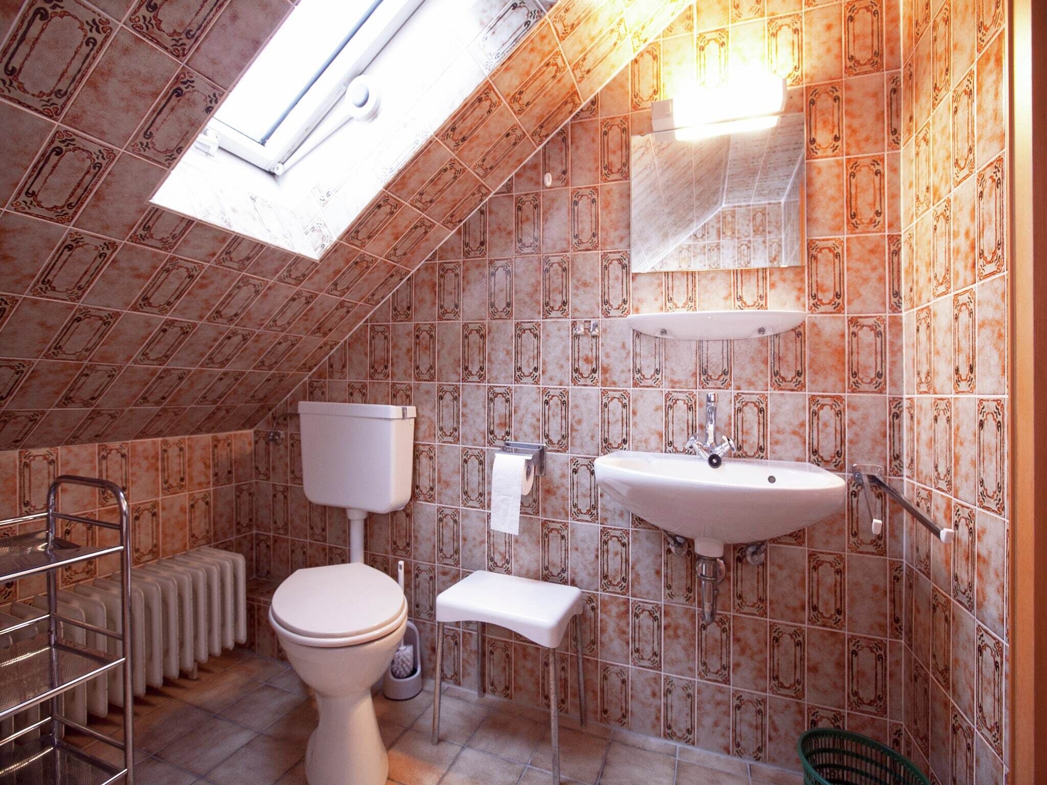 Un baño pequeño con azulejos, un inodoro, un lavamanos y un radiador.