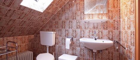Un baño pequeño con azulejos, un inodoro, un lavamanos y un radiador.