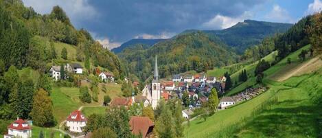 Un village qui se distingue par son église imposante, entouré de collines verdoyantes et sous un ciel dégagé.