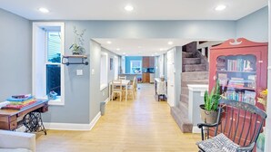A spacious hallway with wooden flooring, a dining area, a staircase, and a bookshelf. - Northern Liberties Epic Retreat-Huge Yard/Fire Pit (Philadelphia)